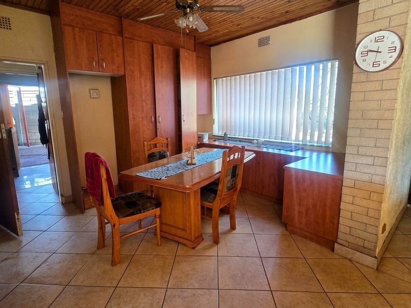 Dining area featuring timber ceilings, tiled floors, a brick feature wall, and extensive built-in wooden cabinetry.