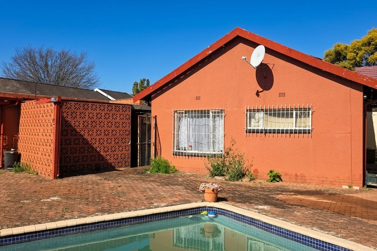 Rear exterior view of the house featuring a swimming pool, brick paved patio area, and security bars on the windows.