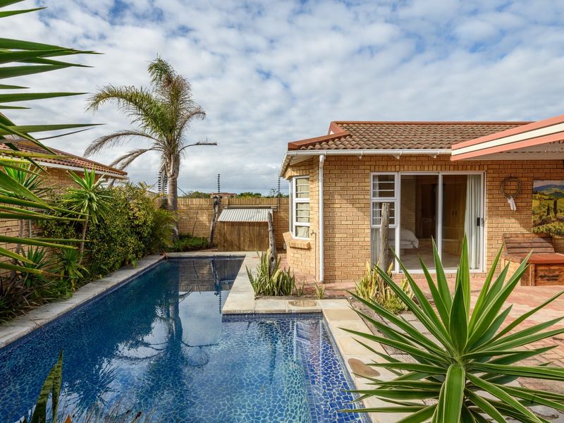 A well-maintained outdoor pool area featuring a paved patio, brick townhouse facade, and secure boundary wall with electric fencing.