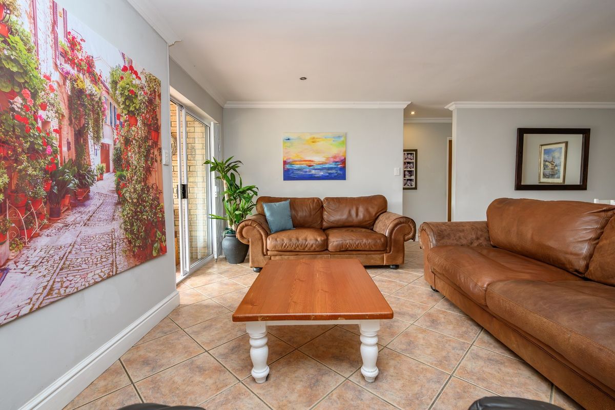 A comfortable living room featuring tiled flooring, recessed lighting, and a sliding glass door providing access to the outdoor area.