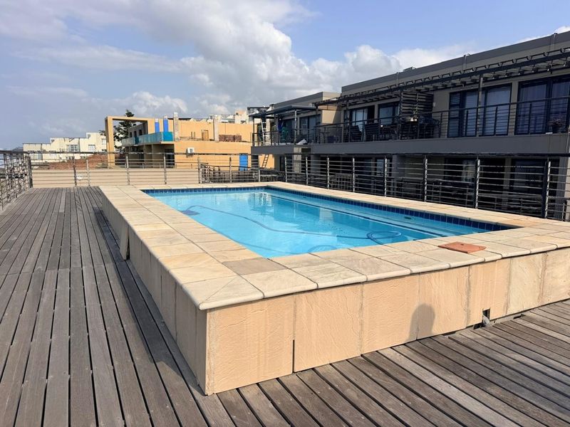 A raised swimming pool set on a timber deck with metal safety railings, offering an elevated outdoor leisure space.