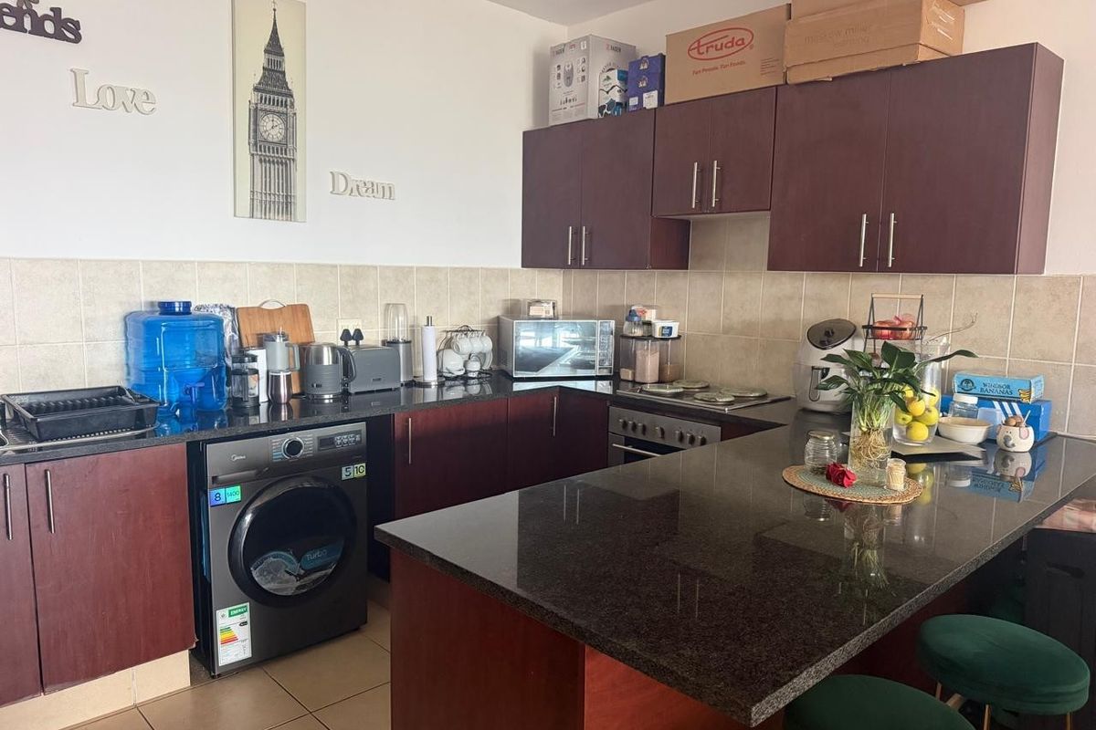 A functional kitchen featuring dark wood cabinetry, granite countertops, a tiled backsplash, and a built-in oven with a breakfast bar area.