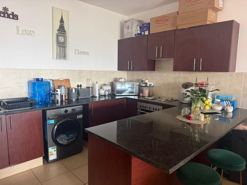 A functional kitchen featuring dark wood cabinetry, granite countertops, a tiled backsplash, and a built-in oven with a breakfast bar area.