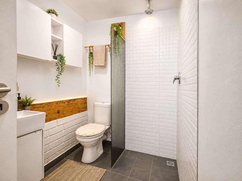 Modern bathroom featuring a walk-in shower with white mosaic tiling, a wall-mounted vanity, and built-in storage cabinetry.
