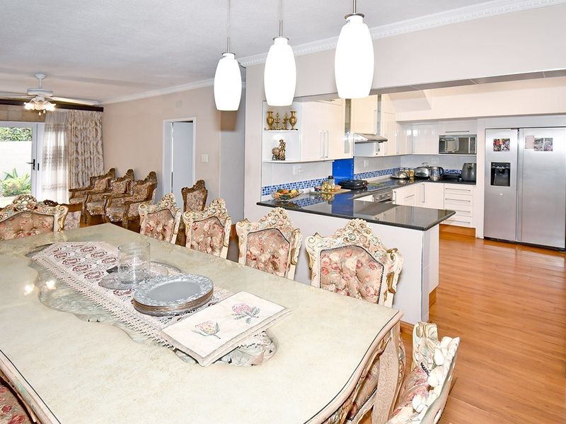 Open-plan living and dining area featuring a modern kitchen with granite countertops, built-in cabinetry, and laminate flooring throughout.