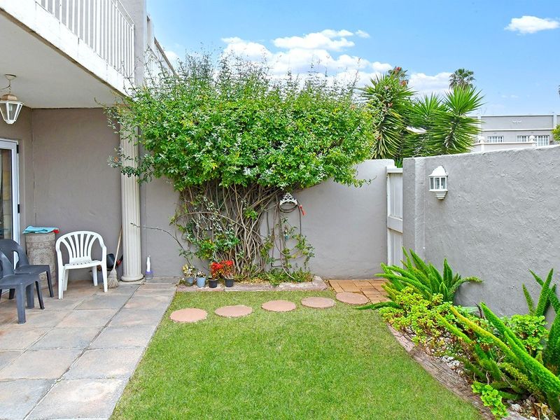 A compact rear garden featuring a paved patio area, a small lawn, and a boundary wall, providing a private outdoor space.