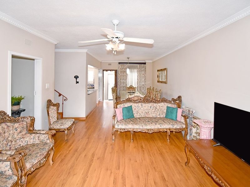 Spacious open-plan living and dining area featuring laminate flooring, crown molding, and a central ceiling fan, providing a versatile layout for family living.