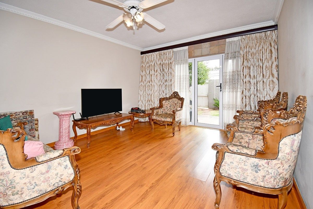A living room featuring laminate flooring, crown molding, a ceiling fan, and a glass door providing access to the exterior.