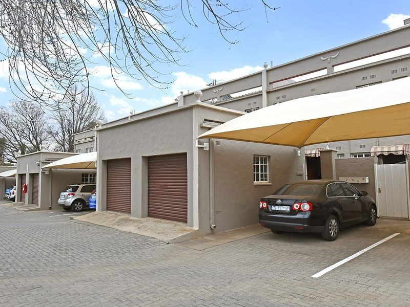 Front exterior view of the property featuring a paved driveway, multiple garage units, and covered carport parking areas.