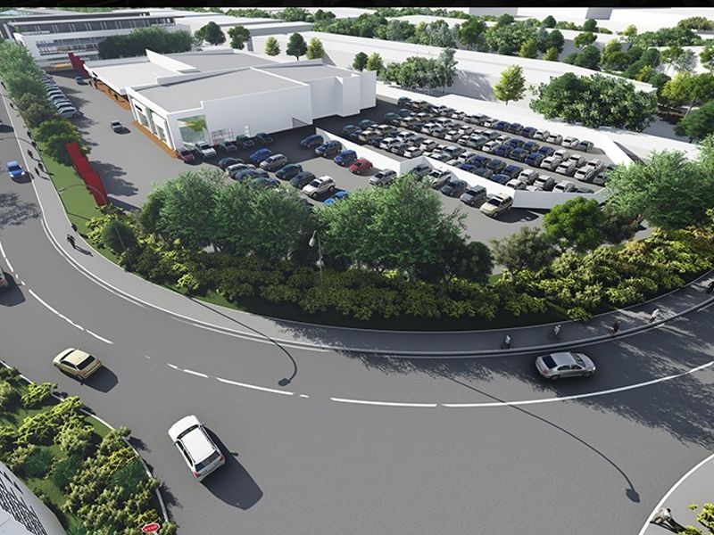 Aerial view of a commercial retail property featuring a large asphalt parking area, landscaped grounds, and direct access from the main road.