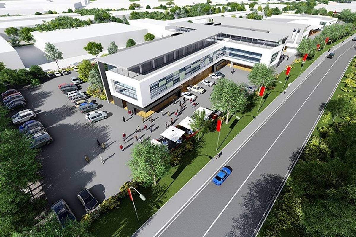 Aerial view of a modern commercial retail complex featuring a multi-story building, extensive asphalt parking facilities, and landscaped surroundings.
