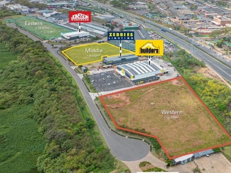 Aerial view of a commercial retail development site featuring multiple plots, existing retail buildings, and paved parking infrastructure adjacent to a major highway.