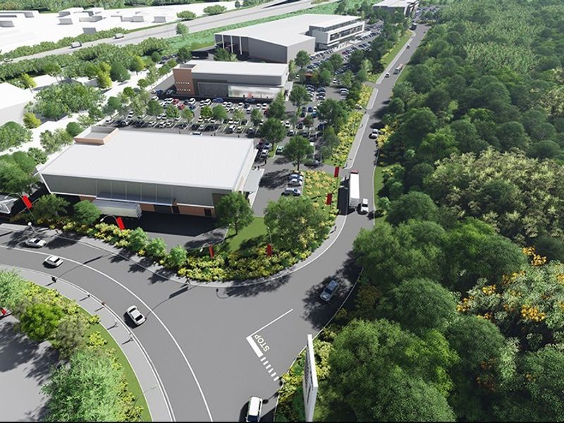 Aerial perspective of a commercial retail development featuring warehouse structures, extensive parking facilities, and surrounding landscaped greenery.