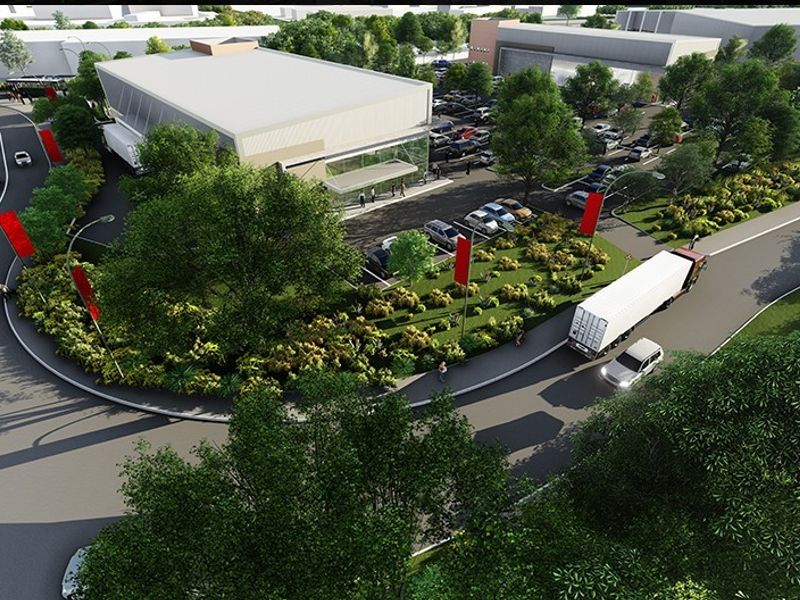 Aerial view of a commercial retail property featuring a large building, dedicated parking area, and landscaped surroundings with road access.