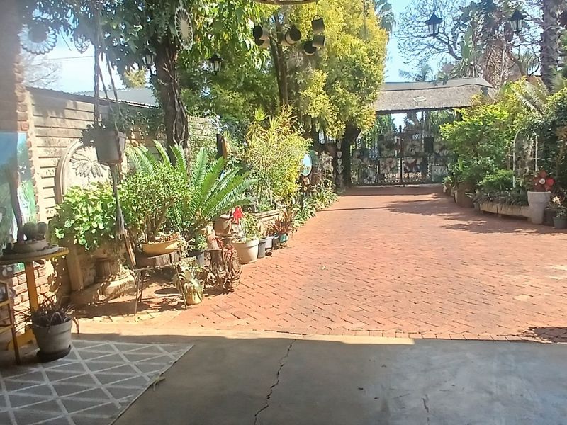 A covered patio area featuring exposed brick walls and brick-paved outdoor space leading to a gated entrance.