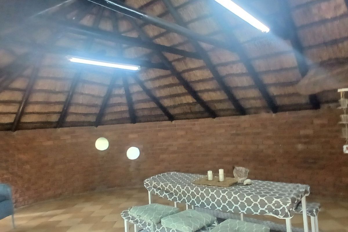 Spacious living area featuring a traditional thatched roof with exposed timber rafters and rustic brick walls, creating a unique and characterful atmosphere.