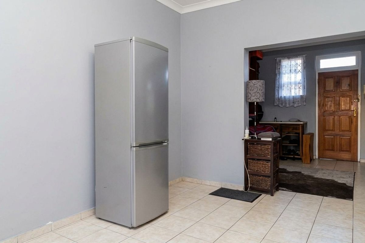 A living area featuring neutral wall paint, tiled flooring, and a solid timber entrance door leading to an adjacent space.