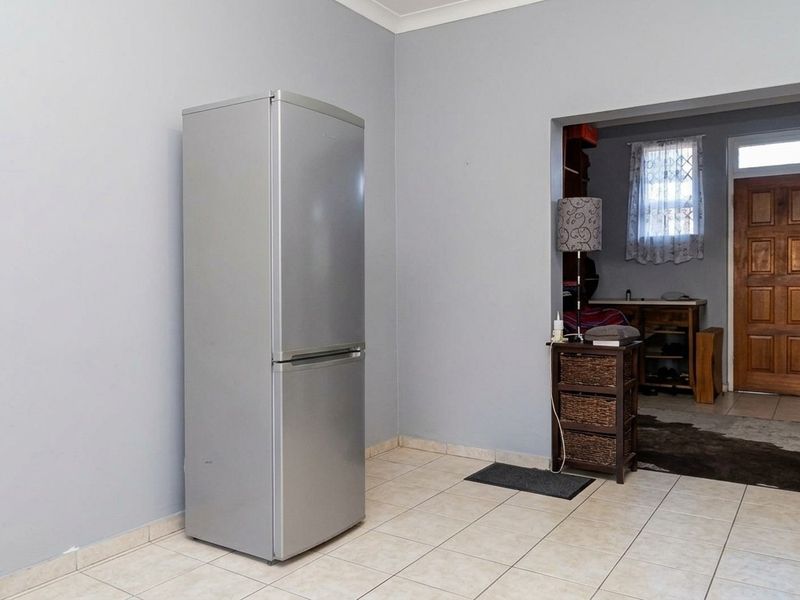 A living area featuring neutral wall paint, tiled flooring, and a solid timber entrance door leading to an adjacent space.