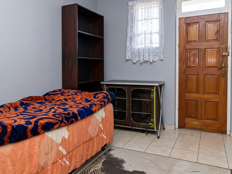 A bedroom featuring tiled flooring, a timber panel door, and a window with security bars.