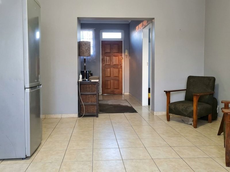 A living area featuring neutral wall tones and tiled flooring, providing a functional space with direct access to the main entrance.