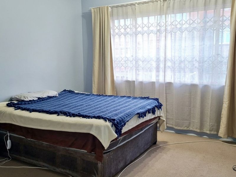 A bedroom featuring carpeted flooring, curtain rails, and a security gate on the window.