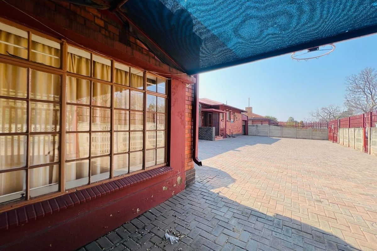 Spacious paved rear courtyard featuring a shade sail, brick exterior walls, and secure perimeter fencing.