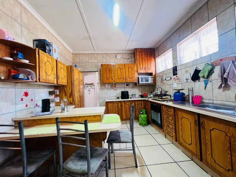 A functional kitchen featuring wooden cabinetry, tiled backsplash, built-in oven and hob, and a breakfast nook area.