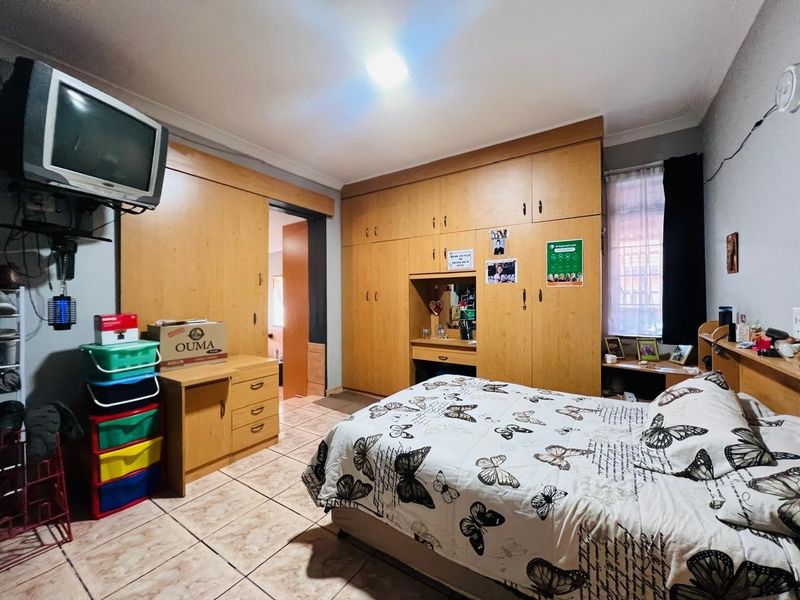 A bedroom featuring extensive built-in wooden cabinetry and tiled flooring, offering ample storage space and a functional layout.
