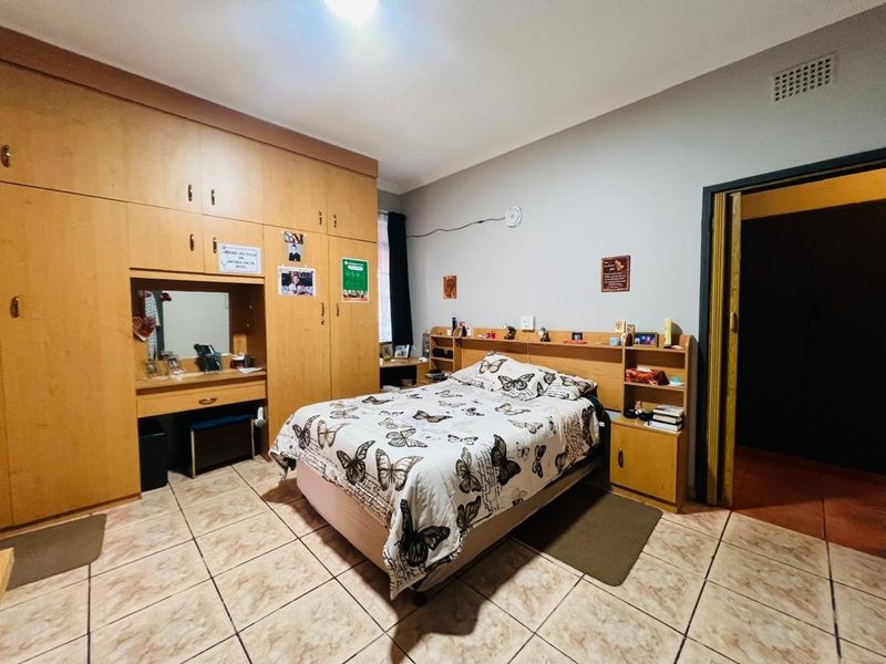 Spacious bedroom featuring extensive built-in cabinetry, a matching built-in headboard, and durable tiled flooring.