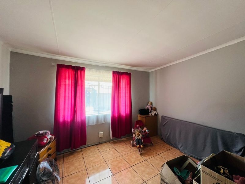 A bedroom featuring tiled flooring, coved ceilings, and a window fitted with security bars.