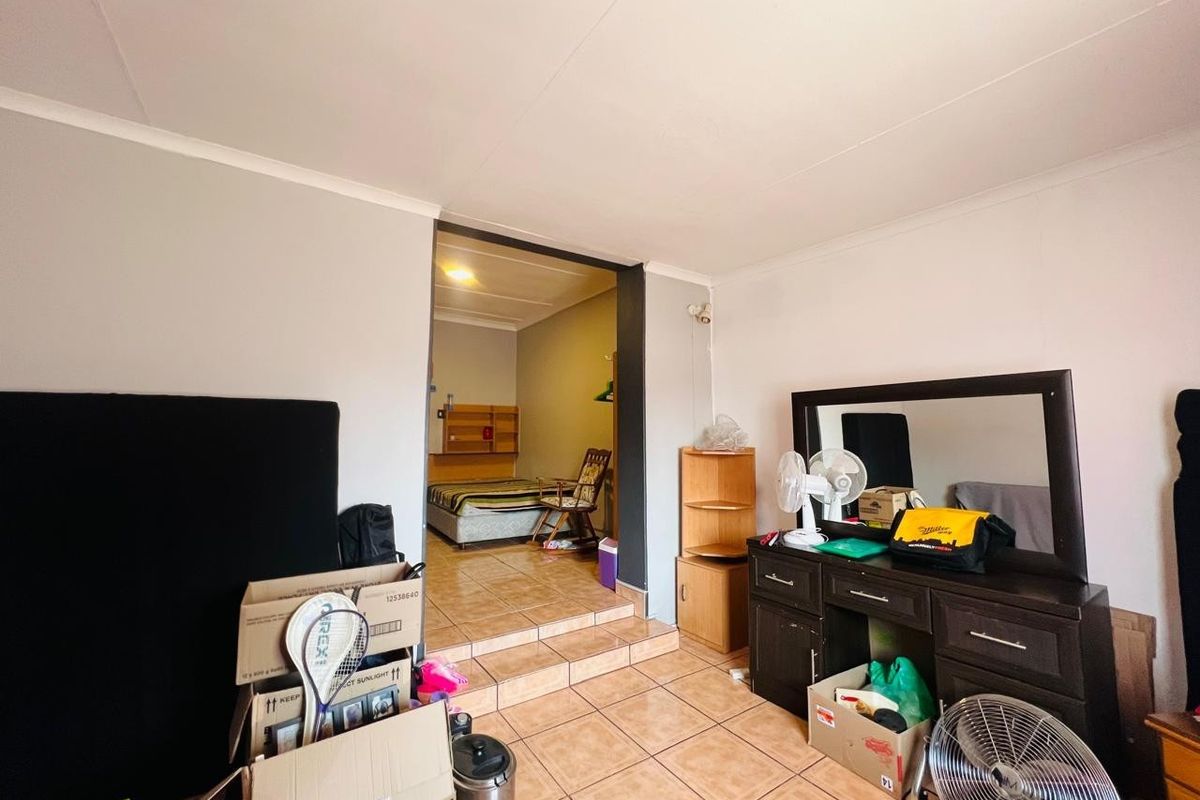 A bedroom space featuring tiled flooring and a raised floor transition leading to an adjoining area.