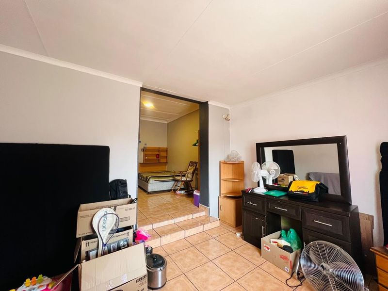 A bedroom space featuring tiled flooring and a raised floor transition leading to an adjoining area.