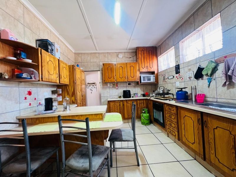 A functional kitchen featuring traditional wooden cabinetry, tiled surfaces, a built-in oven, and a convenient breakfast nook area.