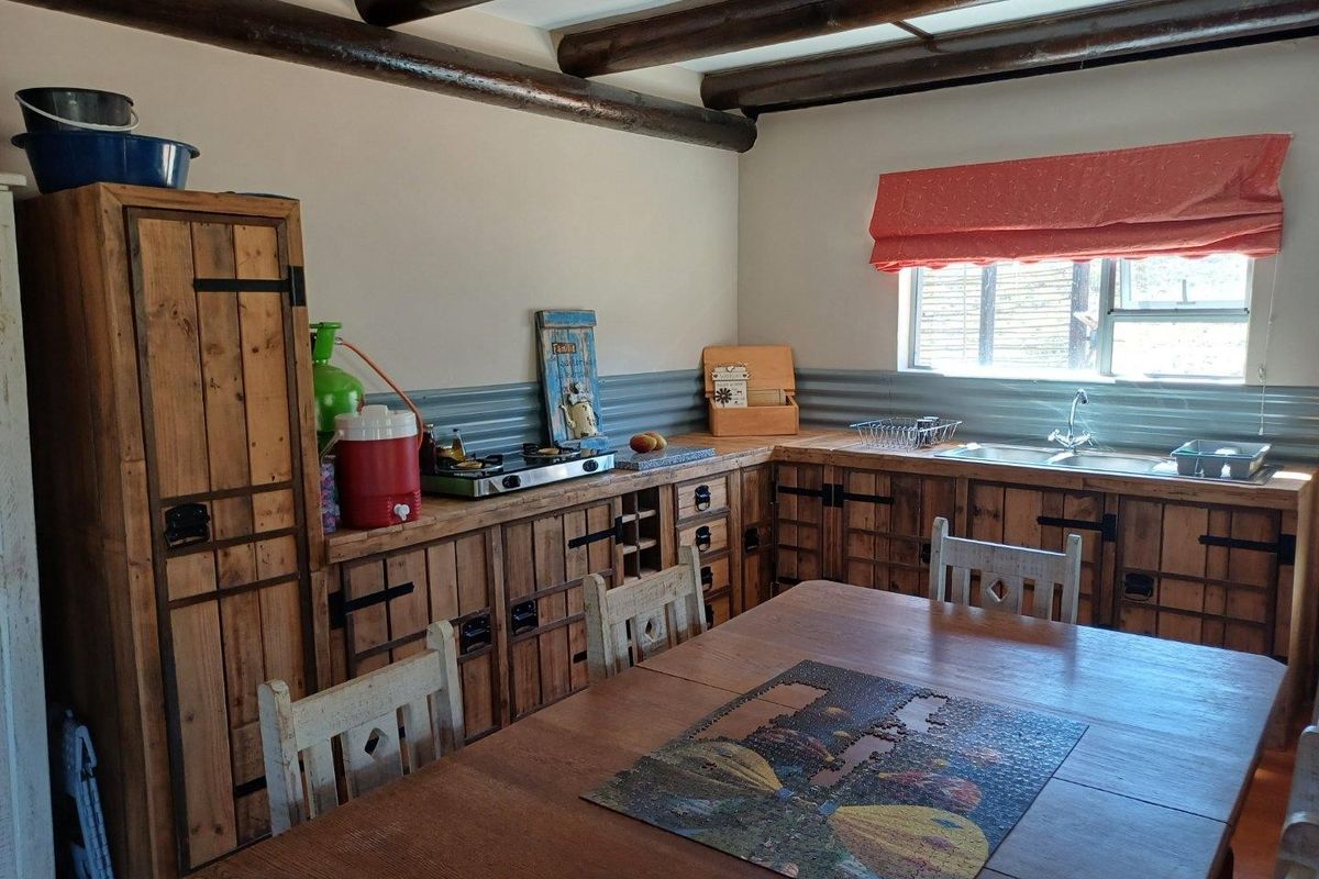 Rustic-style kitchen featuring custom wooden cabinetry, corrugated metal backsplash, and exposed timber ceiling beams, providing a warm and characterful cooking space.