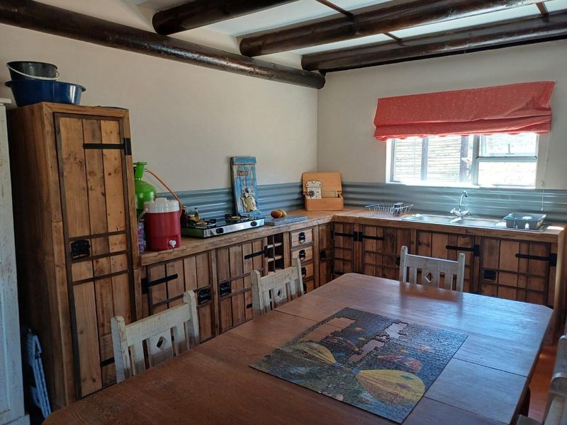 Rustic-style kitchen featuring custom wooden cabinetry, corrugated metal backsplash, and exposed timber ceiling beams, providing a warm and characterful cooking space.