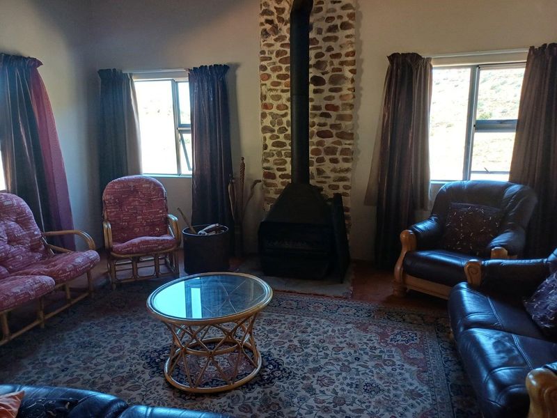 A cozy living room featuring a prominent stone-clad fireplace with a freestanding metal stove and tiled flooring.