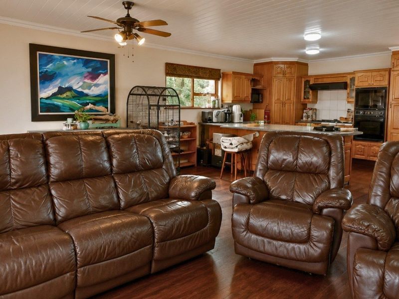 Open plan living and kitchen area featuring timber cabinetry, built-in appliances, a kitchen island, and warm laminate flooring throughout the space.