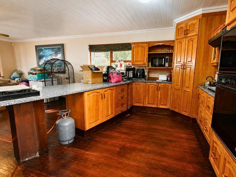 Spacious kitchen featuring warm timber cabinetry, granite countertops, built-in oven, and classic timber flooring, offering a functional layout with ample storage space.