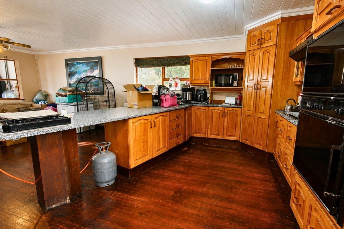 Spacious kitchen featuring warm timber cabinetry, granite countertops, built-in oven, and classic timber flooring, offering a functional layout with ample storage space.