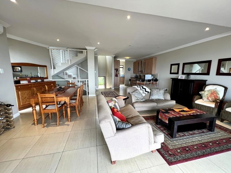 Spacious open-plan living and dining area featuring tiled floors, recessed lighting, and an integrated staircase, flowing into a functional kitchen space.