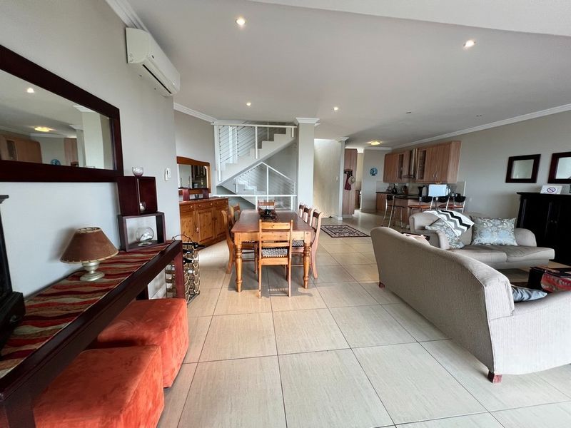Spacious open-plan living and dining area featuring tiled floors, recessed lighting, a split-system air conditioner, and an integrated kitchen with built-in cabinetry.