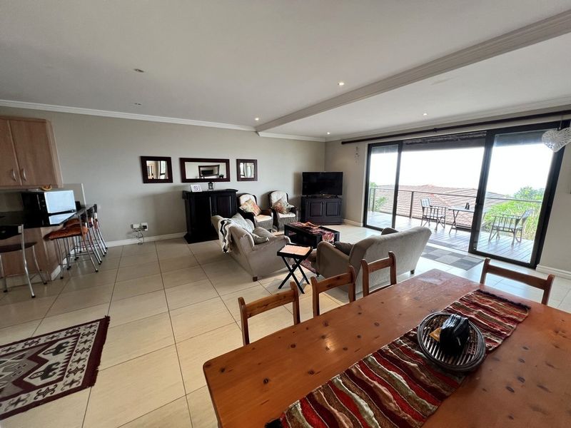 Spacious open-plan living and dining area featuring tiled floors, recessed lighting, and large sliding doors leading to a balcony with scenic views.