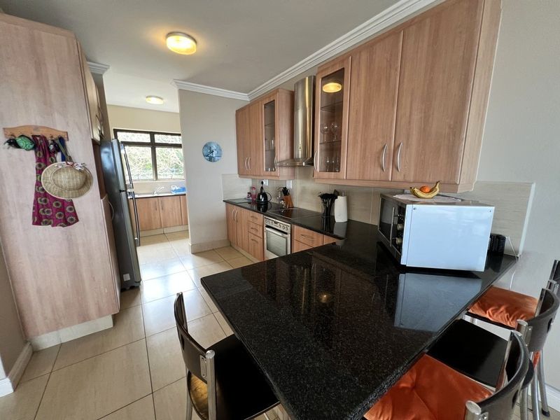 A functional kitchen featuring granite countertops, wood-finish cabinetry, a built-in oven with extractor fan, and a convenient breakfast bar area.