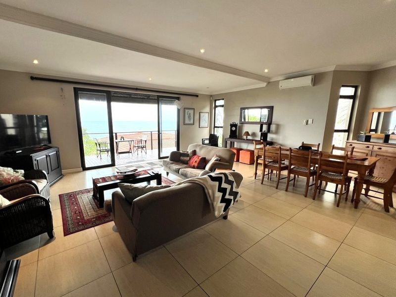 Spacious open-plan living and dining area featuring large sliding glass doors leading to a balcony with scenic views and neutral tiled flooring throughout.