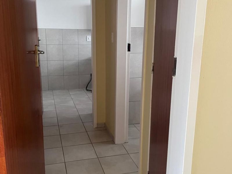 A functional hallway with tiled flooring connecting multiple rooms, featuring neutral wall tones and standard internal door frames.