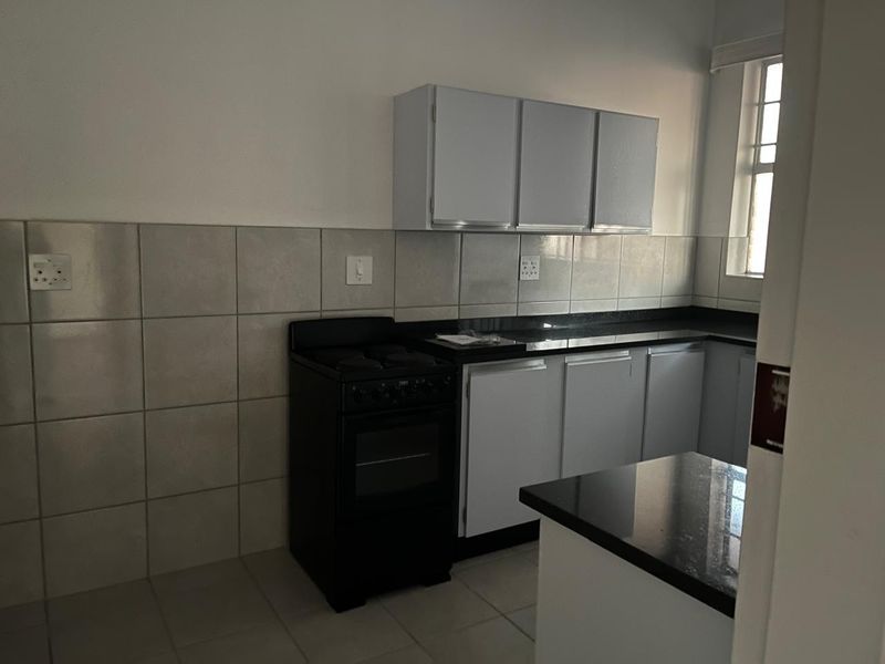 A functional kitchen featuring built-in cabinetry, granite countertops, a tiled backsplash, and a freestanding stove, offering a clean and practical workspace.