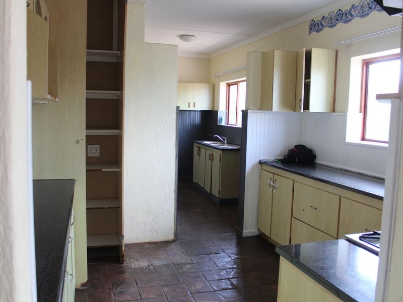 A dated kitchen featuring built-in cabinetry, laminate countertops, and tiled flooring, offering significant potential for a modern renovation.