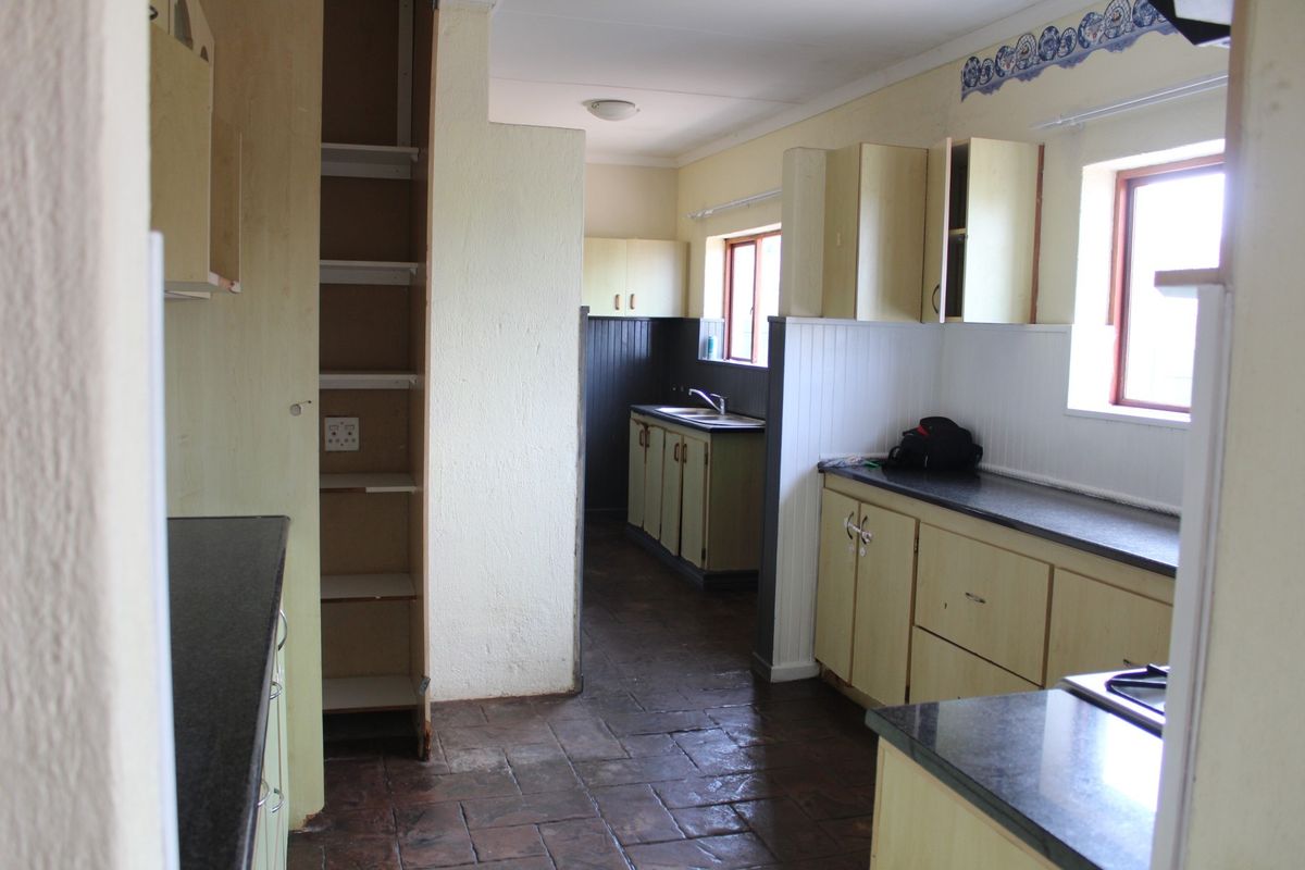 A dated kitchen featuring built-in cabinetry, laminate countertops, and tiled flooring, offering significant potential for a modern renovation.