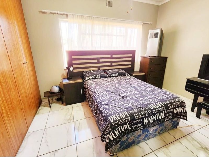 A bedroom featuring tiled flooring and a large built-in wooden wardrobe, providing ample storage space.