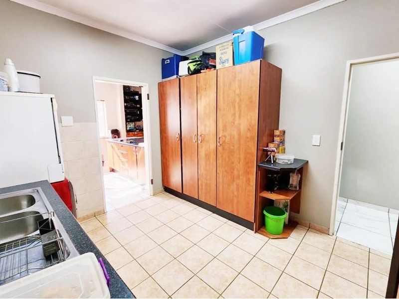 A functional laundry room featuring tiled flooring, built-in storage cabinetry, and a stainless steel sink, providing practical utility space.